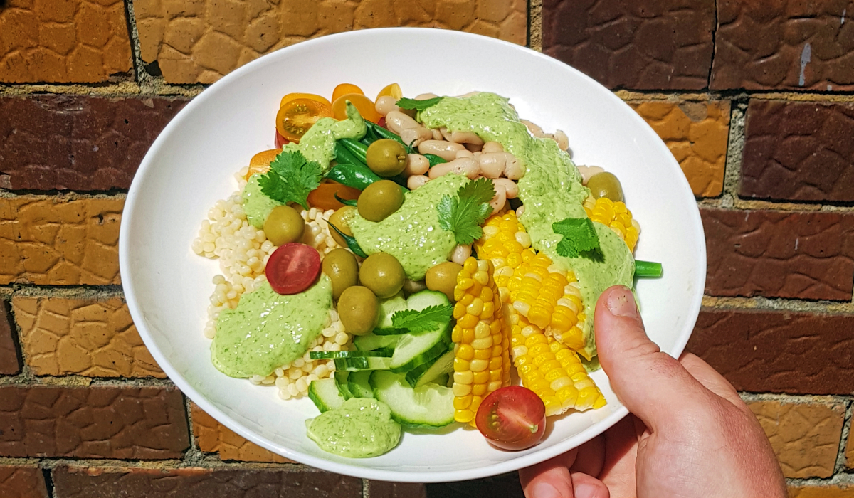 Summer salad with couscous, beans, olives, cherry tomatoes and green goddess dressing
